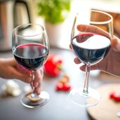 close up photo of two people toasting with red wine