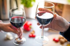 close up photo of two people toasting with red wine