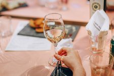 person holding wine glass near clear shot glasses