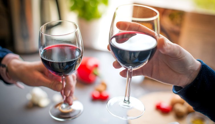 close up photo of two people toasting with red wine