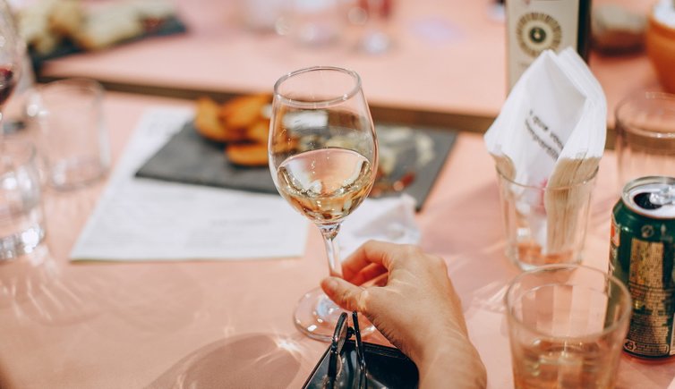 person holding wine glass near clear shot glasses